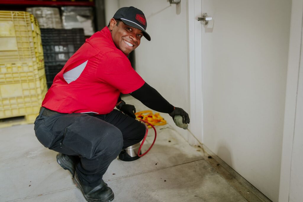 Red Pest Control technician applying pest treatment at residential property
