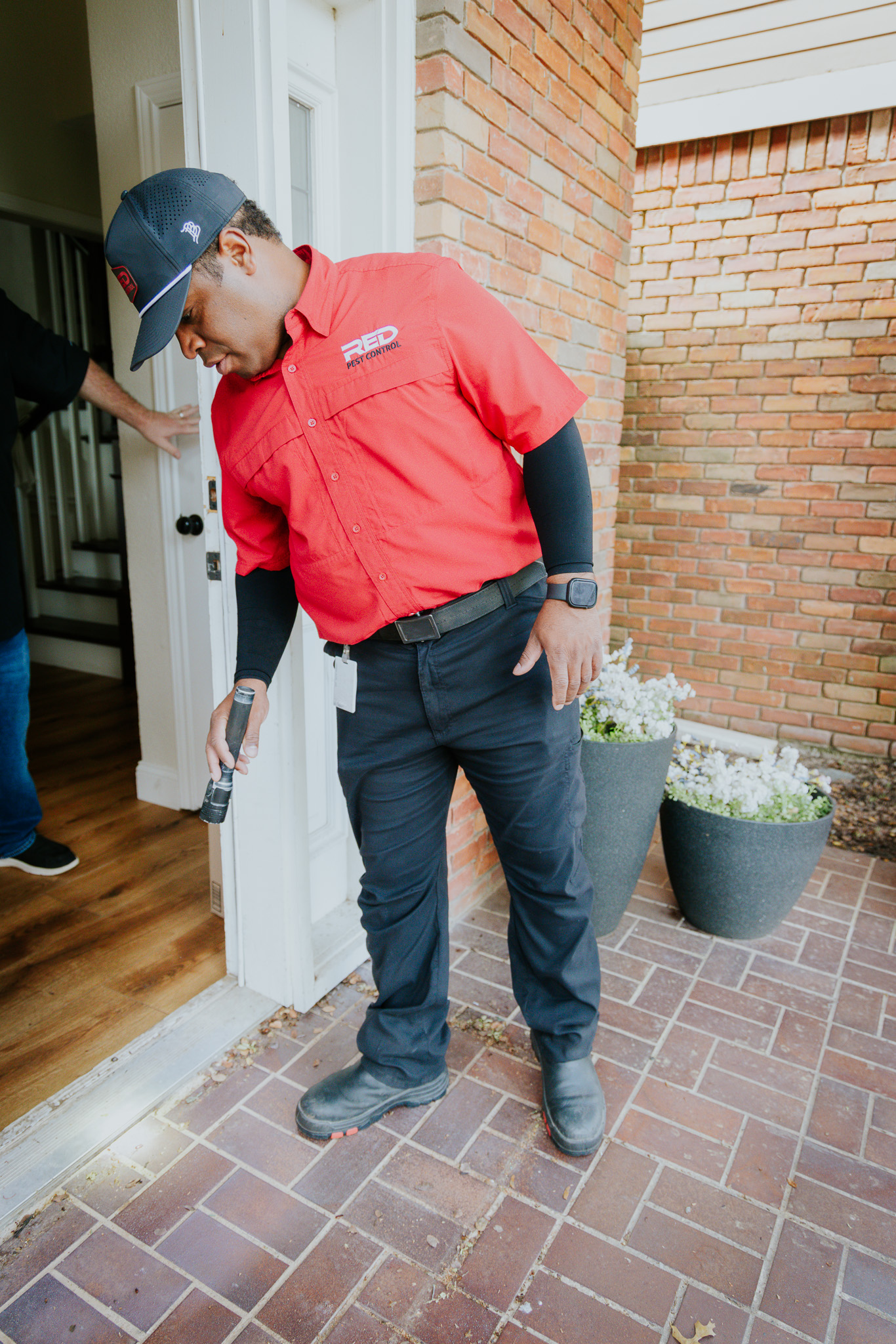 Red Pest Control technician inspecting a home